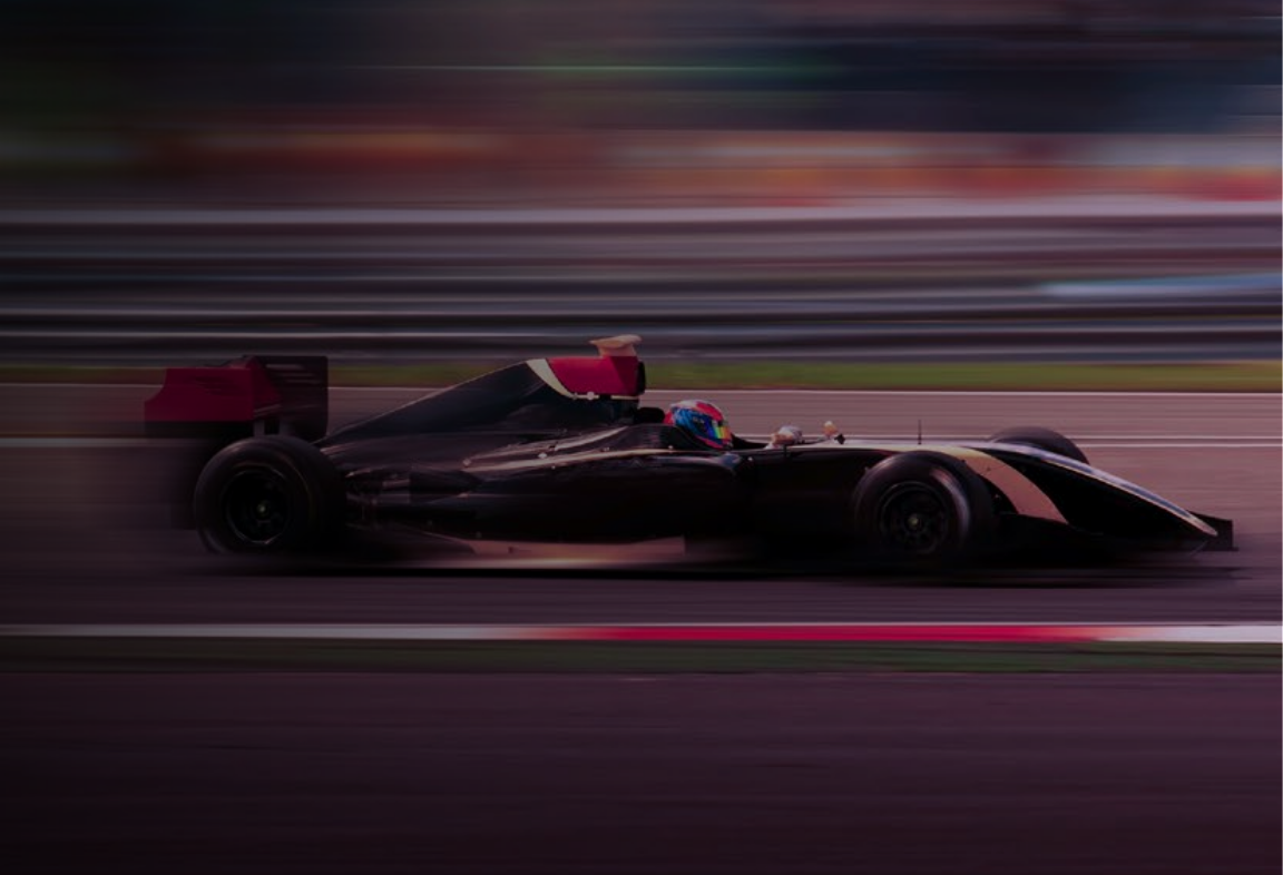 Formula 1 race car speeding on track with motion blur effect, driver wearing colorful helmet.