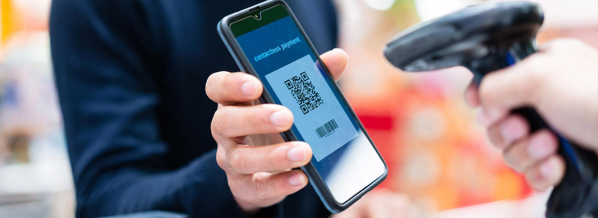 man holding cell phone showing QR code for payment